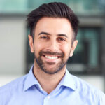 portrait-of-smiling-businessman-standing-in-lobby-3QPCMXE-150x150